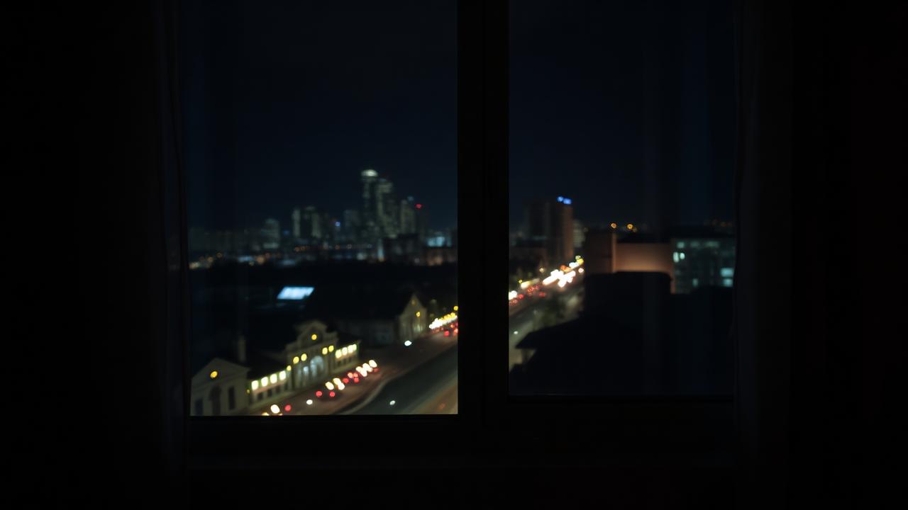 bedroom window with city lights and nighttime traffic noise