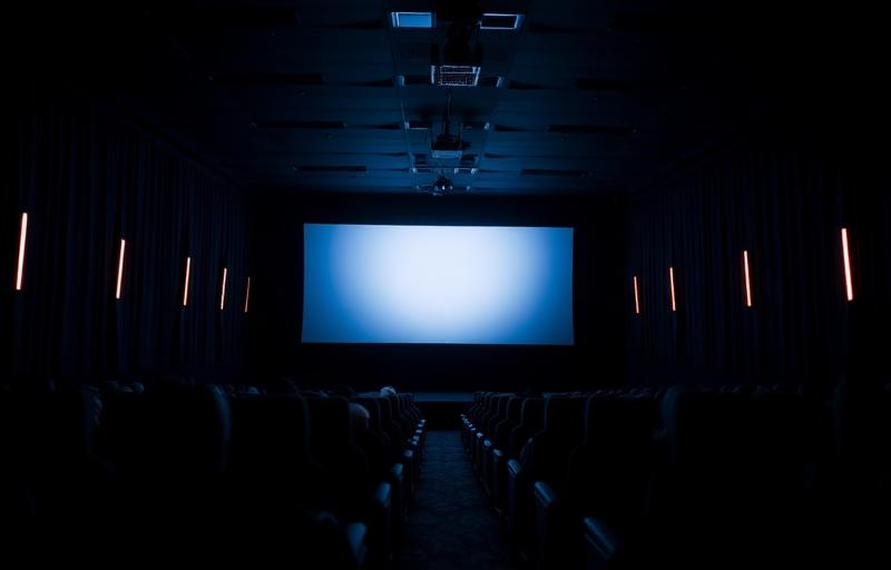 Movie theater interior during a film showing with bright screen and seated audience